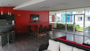 Ein modernes Interieur mit roter Akzentwand, einem Flachbildfernseher und einer Sitzecke mit Sofa und Sesseln.