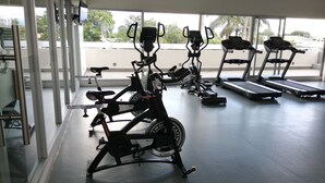 Ein Fitnessstudio mit Ergometer und Laufbändern, großen Fenstern und Blick ins Freie.