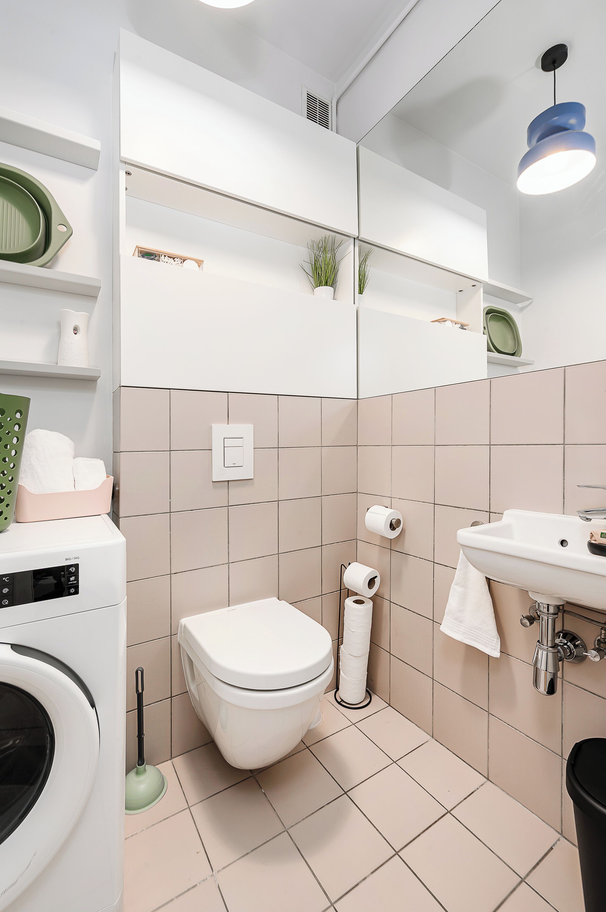 Une salle de bain moderne équipée de toilettes, d’un lavabo et d’un lave-linge.