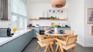 Une cuisine moderne dotée d’un îlot central, d’appareils électroménagers intégrés et d’un coin repas avec des chaises en bois et une table ronde.
