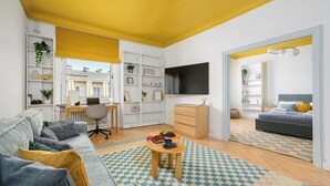 Un salon moderne avec un canapé, une table basse et un téléviseur. On y trouve également un bureau avec une chaise et une bibliothèque.