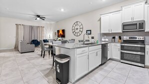 A modern kitchen with white cabinets, a built-in oven, and a microwave.
