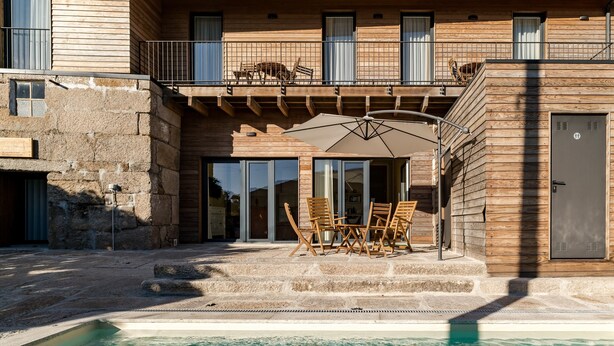 Ein Poolbereich mit Holzterrasse, Gartenmöbeln und Schwimmbecken.