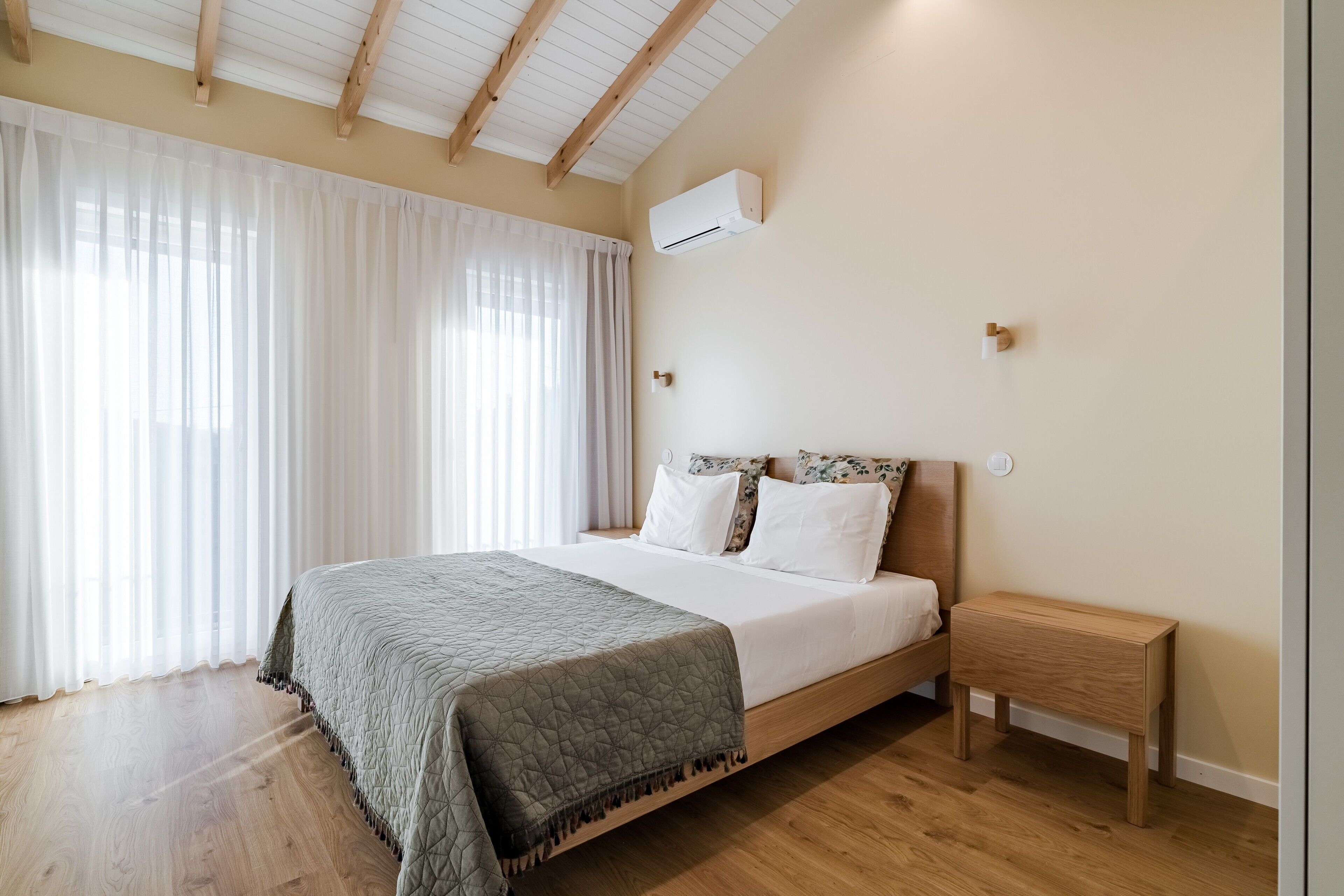 A bedroom with a bed, bedside table, and an air conditioning unit.