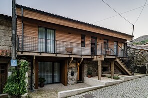 Een gebouw met twee verdiepingen, een houten gevel, een balkon en een stenen trap.