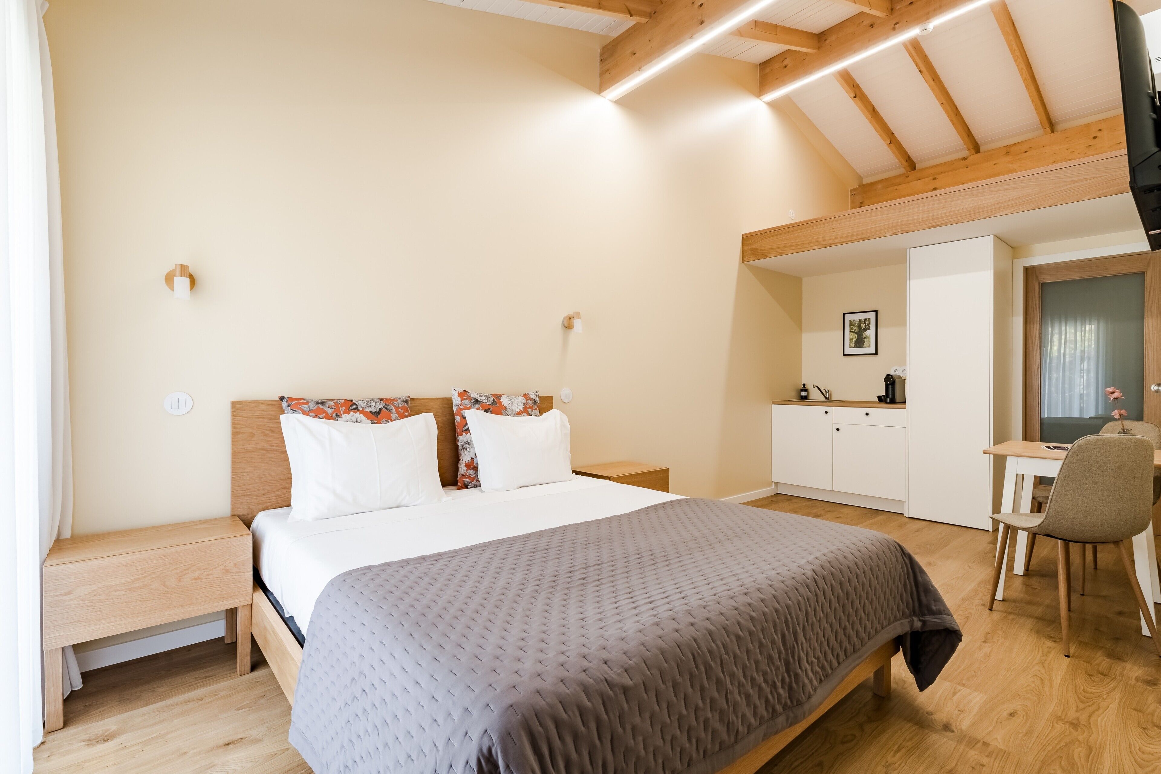 Ein Schlafzimmer mit Bett, Nachttisch, Schreibtisch, Stuhl und einer kleinen Küche.