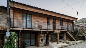 Un bâtiment à deux étages doté d’une façade en bois, d’un balcon et d’un escalier en pierre.