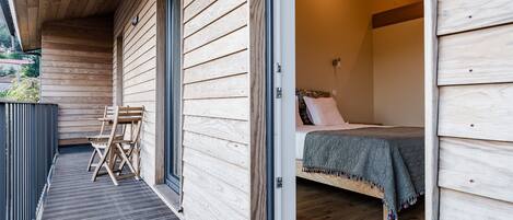 A wooden cabin with a bed, a small table, and chairs on a porch.