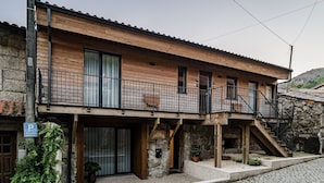 A two-story building with a wooden facade, a balcony, and a stone staircase.