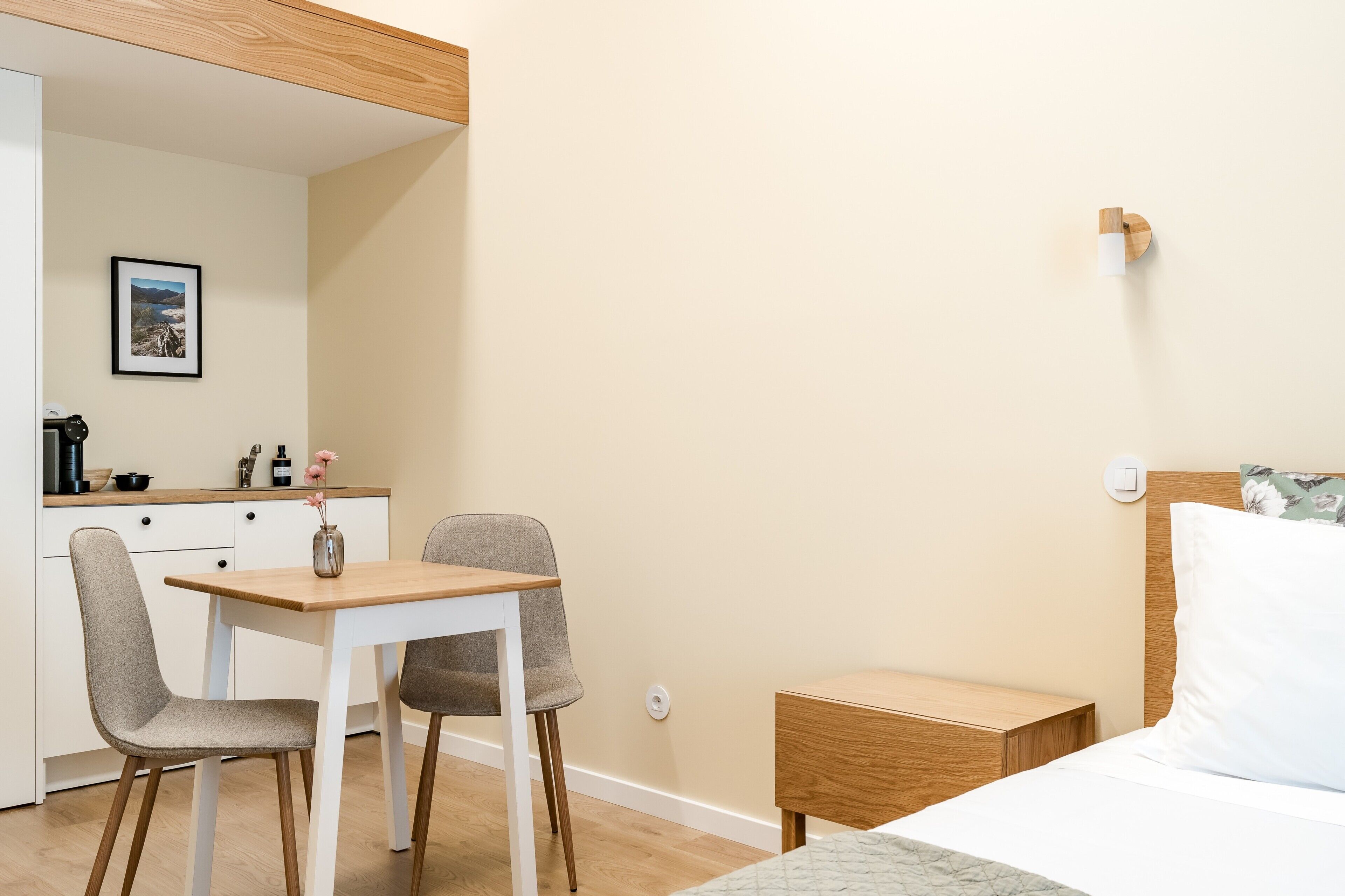 Une chambre d’hôtel comprenant un lit, une table de chevet, une commode et un coin repas avec une table et des chaises.