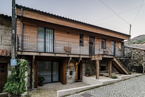 Un edificio de dos pisos con fachada de madera, un balcón y una escalera de piedra.