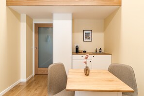 A small, modern room with a wooden dining table, two chairs, a white cabinet, and a door leading to another room. - 'Avó Custódia - Room' with Mountain View, Wi-Fi and Air Conditioning (Terras de Bouro)