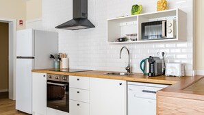 Une cuisine compacte équipée d’un four encastré, d’un four à micro-ondes, d’un évier et d’un lave-vaisselle.