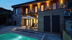 Une maison à deux étages dotée d’un patio couvert, d’un espace salon extérieur et d’une piscine.