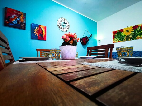 A dining table with chairs, a clock, and artwork on the walls.