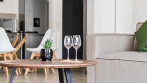 Ein modernes Wohnzimmer mit einem runden Holztisch, zwei Weingläsern und einem kleinen Blumentopf.