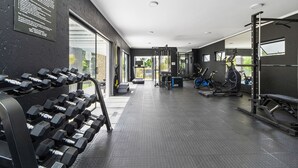 Ein Fitnessstudio mit Reihen von Kurzhanteln, Cardiogeräten und Krafttrainingsgeräten.