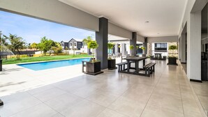 Ein großzügiger Patio-Bereich mit Schwimmbad, Gartenmöbeln und Blick auf die Nachbarhäuser.