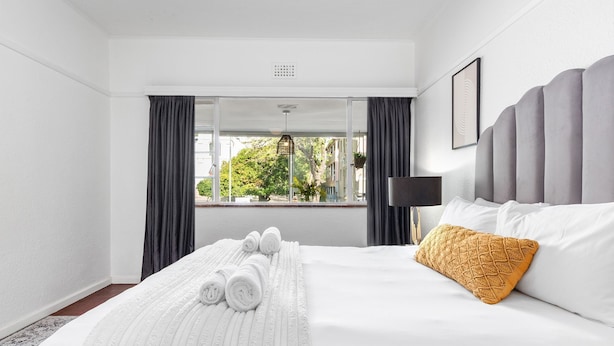 Ein Hotelzimmer mit einem großen Bett, Blick durch ein Fenster und einer Nachttischlampe.