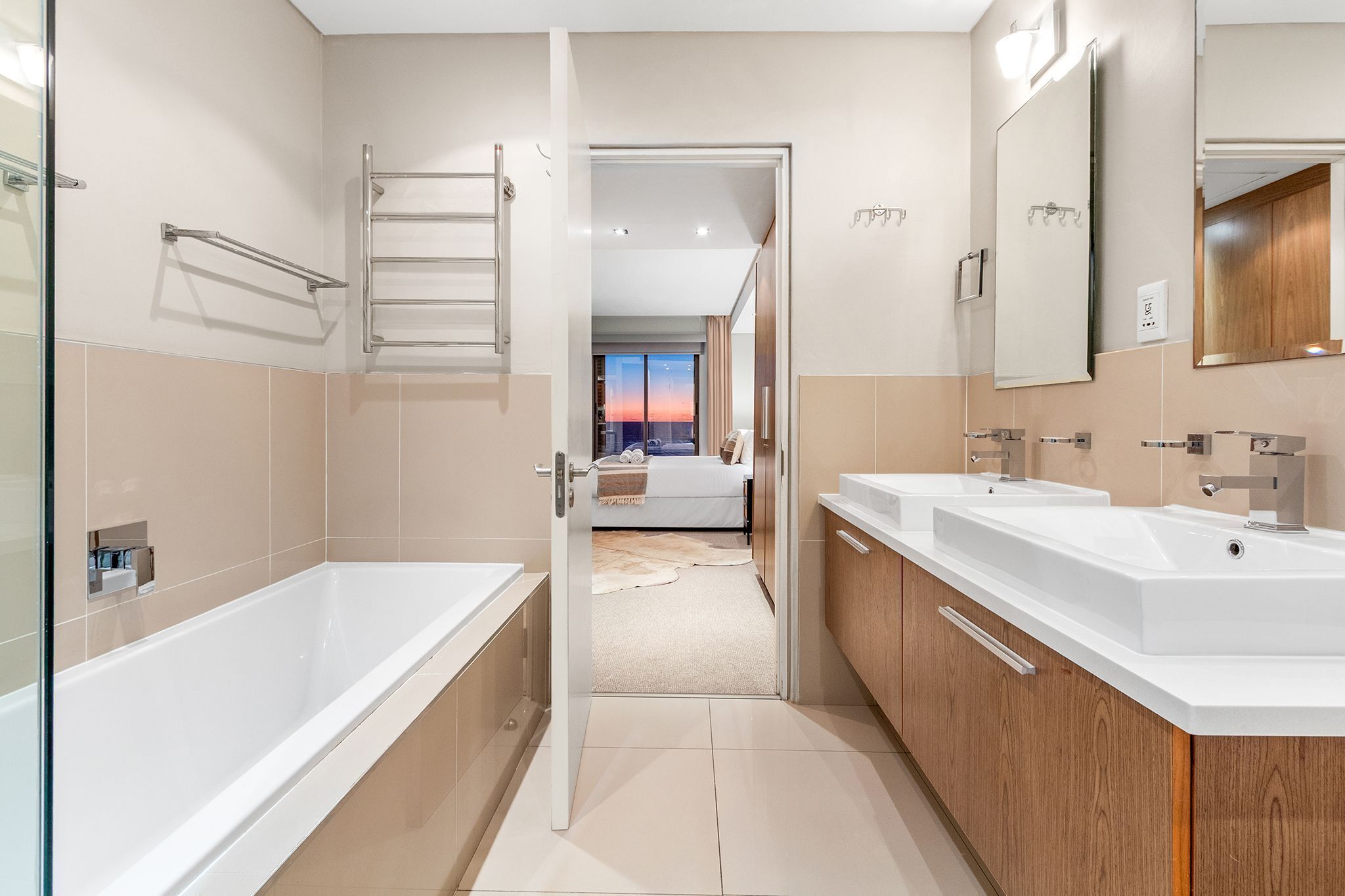 A modern bathroom with a bathtub, two sinks, and a large mirror.