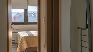 En korridor som leder till ett sovrum med en säng, en stor spegel och utsikt över omgivningen.
