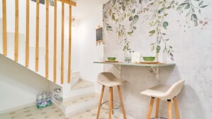 A staircase with wooden railings, a small table with stools, and a wall with a floral mural. - Holiday Home 'Casa El Camaleón' with Wi-Fi and Air Conditioning (Almuñecar)