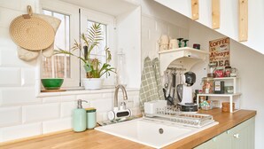 A kitchen with a wooden countertop, white sink, and a window with a potted plant. - Holiday Home 'Casa El Camaleón' with Wi-Fi and Air Conditioning (Almuñecar)