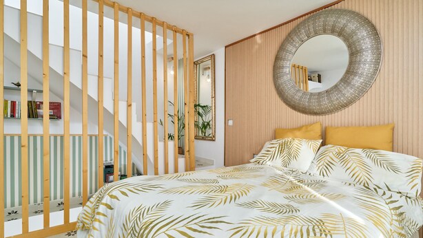 A bedroom with a bed, a large mirror, a wooden partition, and a staircase. - Holiday Home 'Casa El Camaleón' with Wi-Fi and Air Conditioning (Almuñecar)