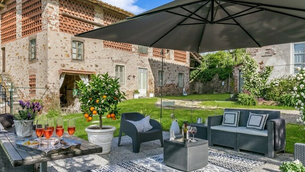 An outdoor patio with a table set for dining, outdoor furniture, and a large umbrella. - Charming 52 sqm Apartment – Romantic Nest with Exclusive Kitchen (Lucca)