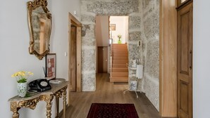 Ein Flur mit einem Marmorkonsolentisch, einem Telefon, einer Blumenvase, einem Spiegel und einer Treppe, die in einen anderen Raum führt.