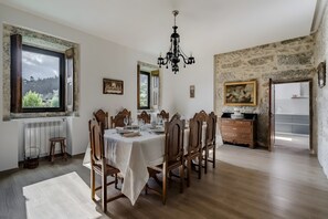 A dining room with a table set for six, wooden chairs, a chandelier, and a view of the outdoors through a window. - Holiday Home 'Quinta Do Bairro - Rés Do Chão' with Mountain View, Wi-Fi and Air Conditioning (Rossas)