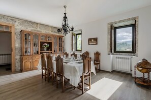 A dining room with a chandelier, wooden cabinets, and a large window with a view.