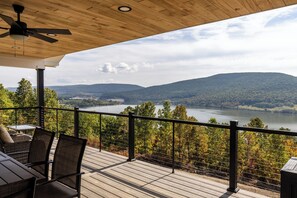 Una terraza de madera con vistas a un lago y montañas.
