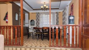 A dining area with a checkered floor, wooden chairs, and a chandelier.
