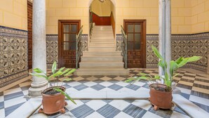 Un sol à carreaux, un escalier et des plantes en pot.