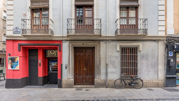 Un bâtiment avec une entrée rouge, une porte en bois et un vélo garé à l’extérieur.