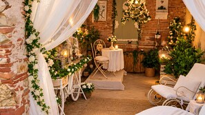 A cozy, rustic room with a brick wall, white drapes, and a white chair. - Family Suite 67sqm with Private Gazebo and Romantic Bathroom (Lucca)