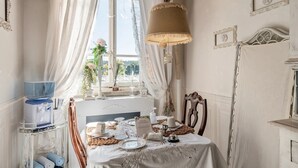Una stanza con un tavolo apparecchiato per un pasto, una finestra con tende e una lampada.