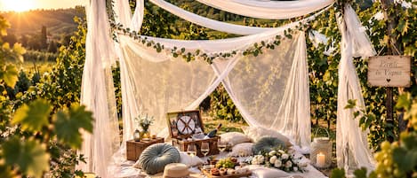 A picnic setup in a vineyard with a canopy, wicker furniture, and a sign reading 'Picnic in Vigna'.