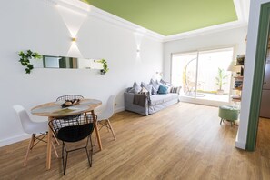 Un salon lumineux avec un coin repas, un canapé gris et un plafond vert.