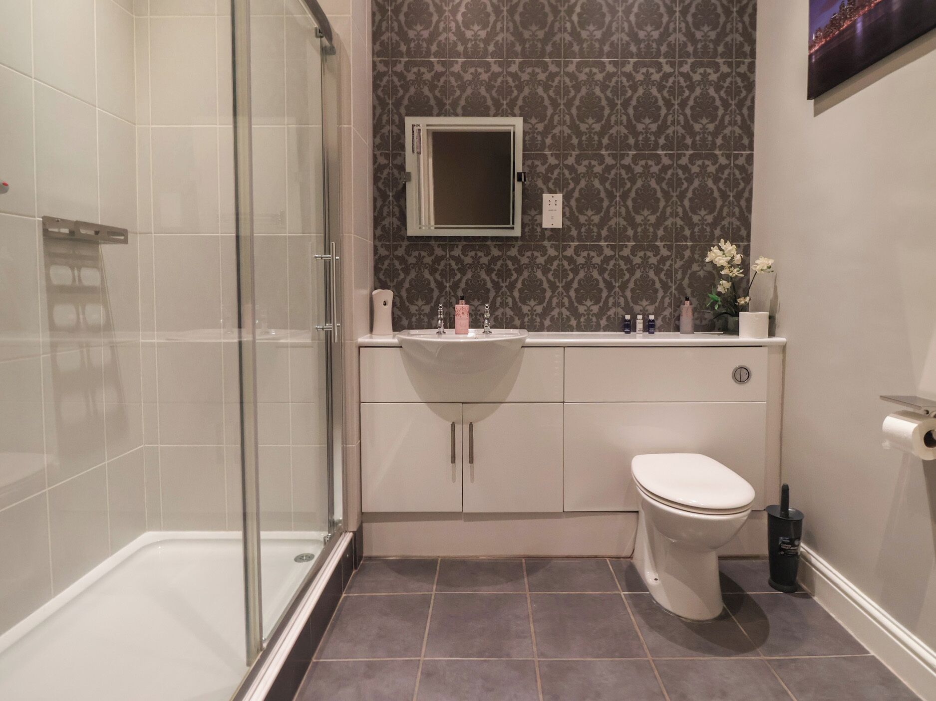 Une salle de bain moderne avec une douche à parois de verre, un lavabo blanc et des toilettes.
