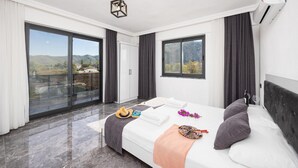 A modern hotel room with a large bed, a balcony with a glass door, and a city view. - Villa Grand Yasar 1 With 4 Bedrooms and 4 Bathrooms (Ortaca)