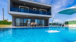 A modern two-story house with a swimming pool, a waterfall feature, and outdoor seating. - Villa Grand Yasar 1 With 4 Bedrooms and 4 Bathrooms (Ortaca)