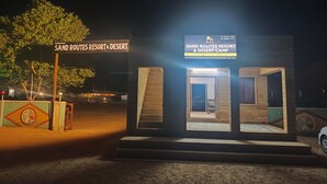Un piccolo edificio illuminato con un cartello che riporta la scritta "SAND ROUTES RESORT & DESERT CAMP".