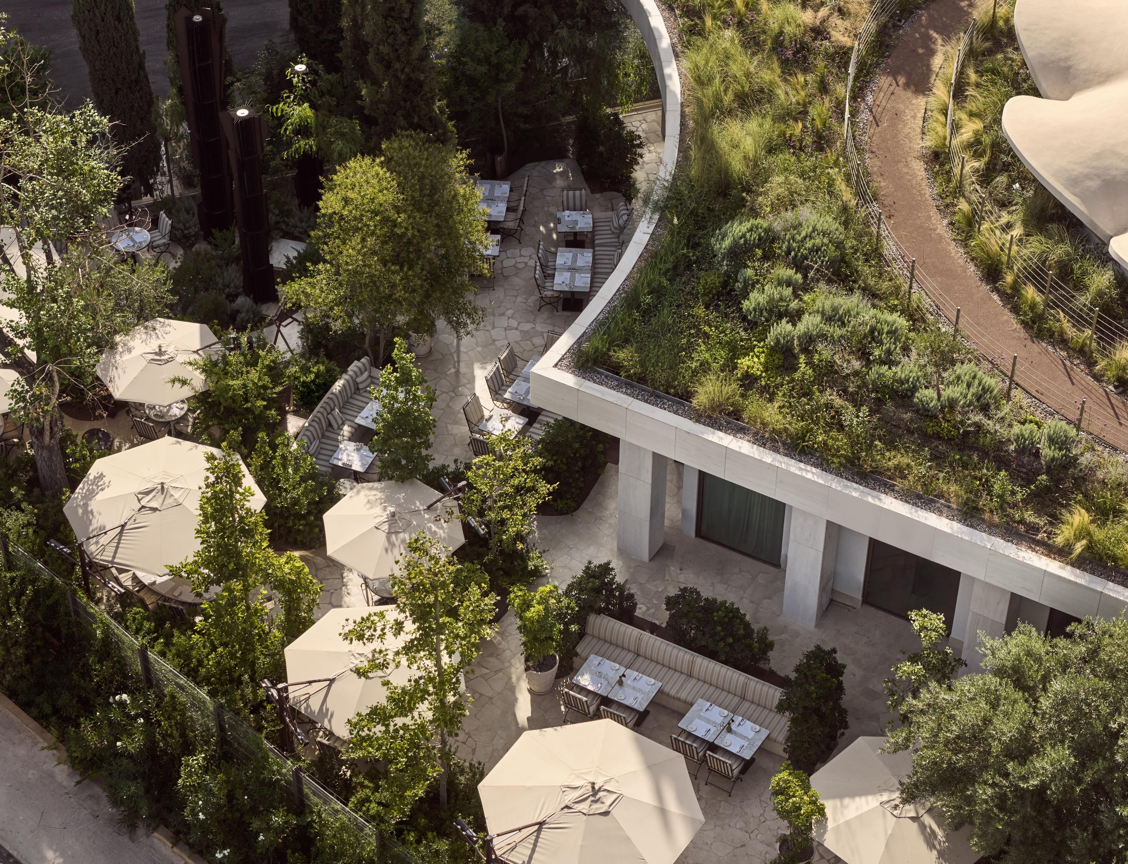 An outdoor seating area with tables and chairs, surrounded by greenery and trees.
