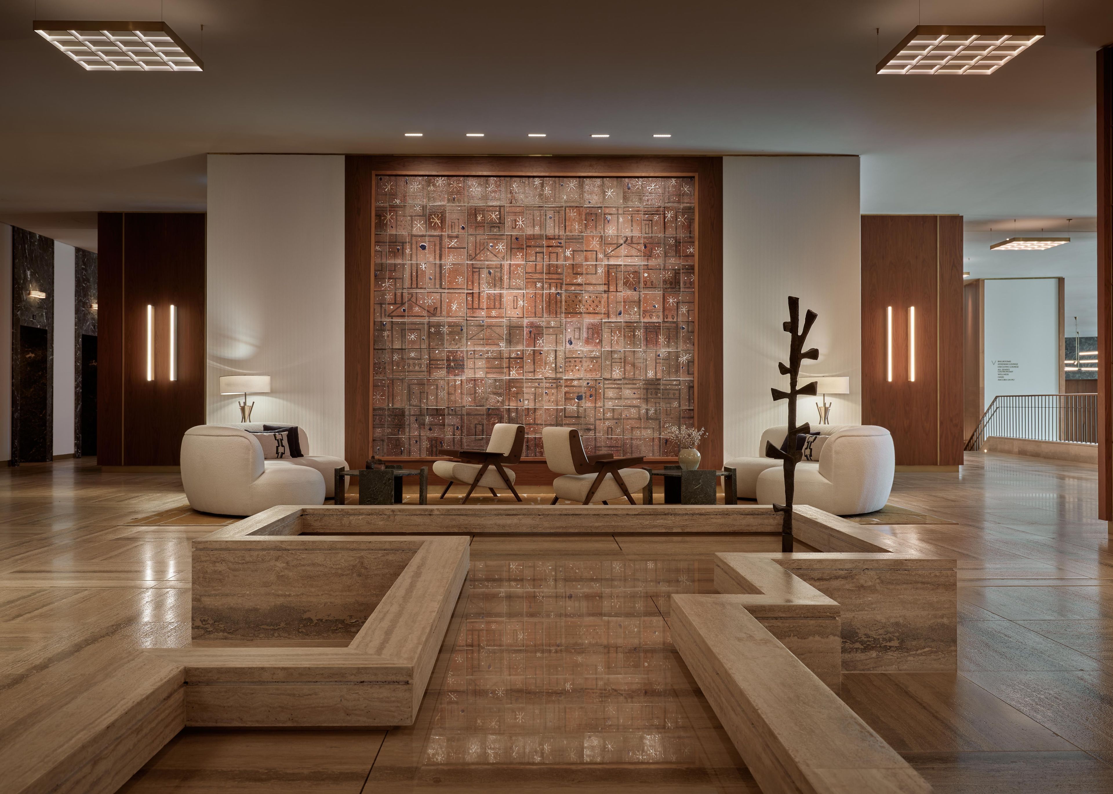A modern lobby with a central seating area, wooden flooring, and a decorative wall.