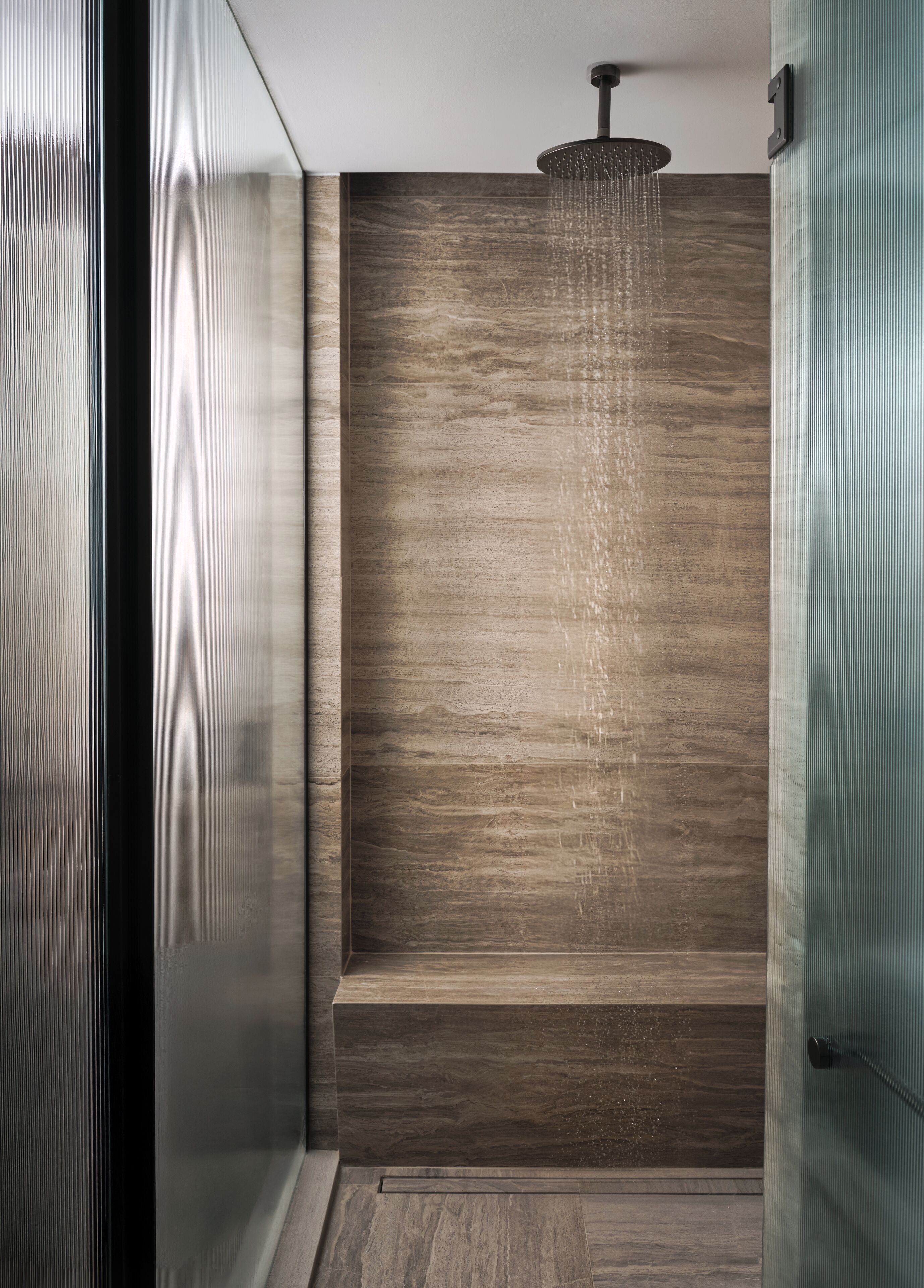 A modern shower with a wooden panel wall and a rain showerhead.