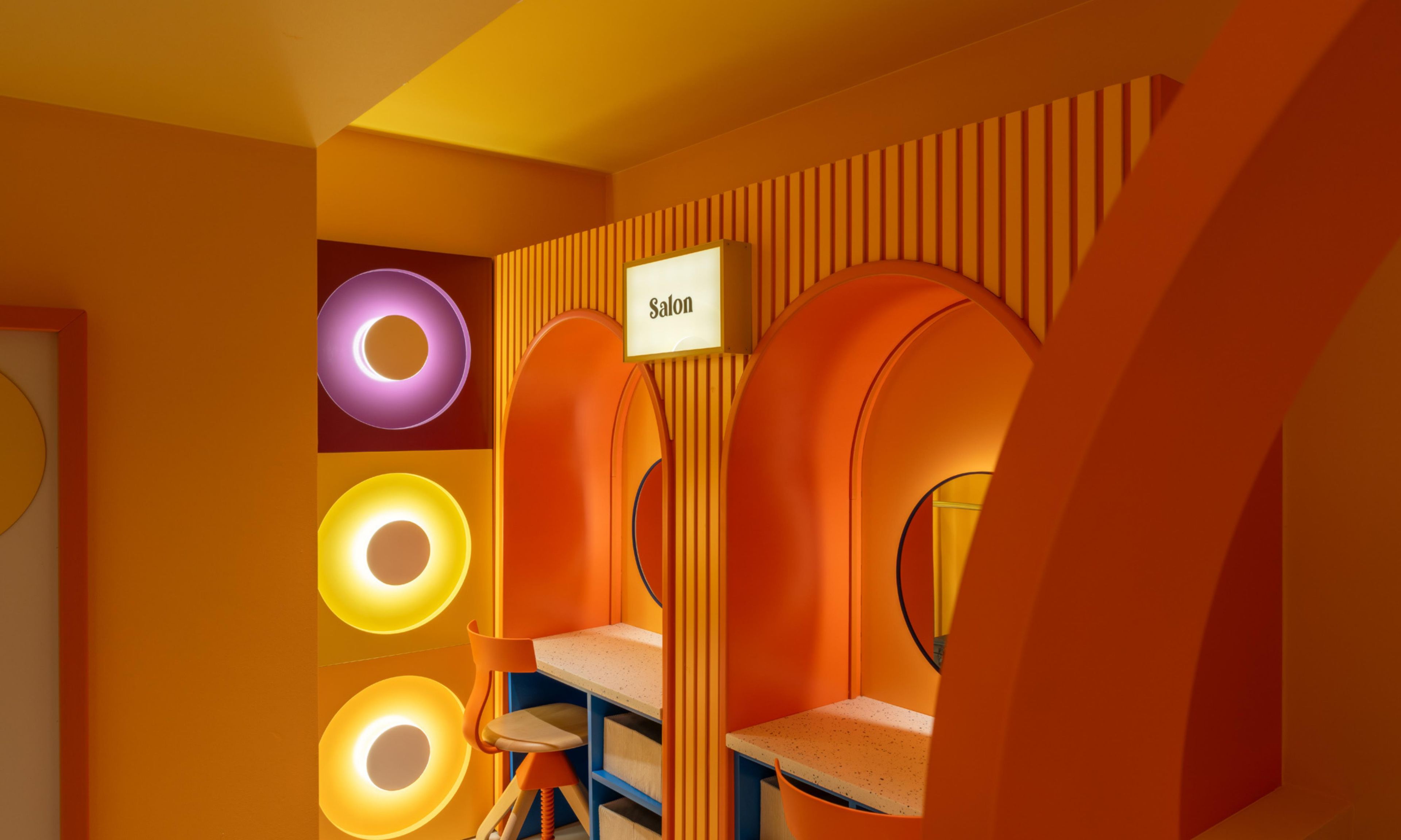 Une pièce avec une enseigne indiquant « Salon », des luminaires circulaires et un fauteuil.