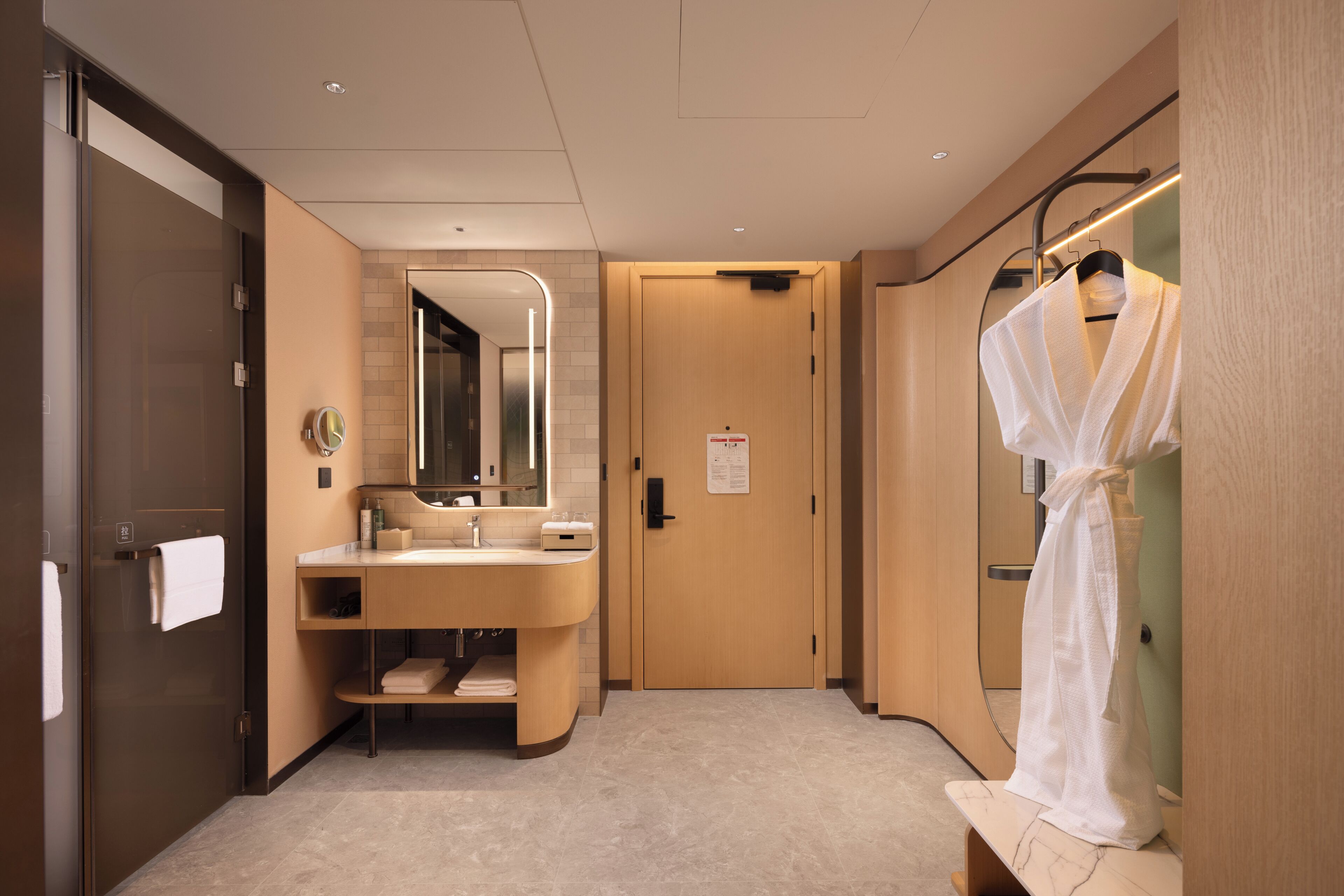 Une salle de bain moderne avec un meuble-lavabo, un miroir, un porte-serviettes et un peignoir suspendu à un porte-manteau.