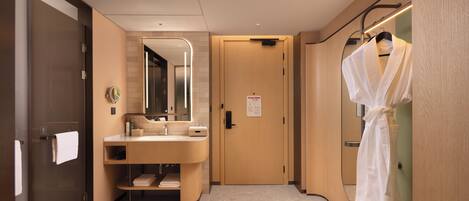 A modern bathroom with a vanity, mirror, towel rack, and robe hanging on a rack.